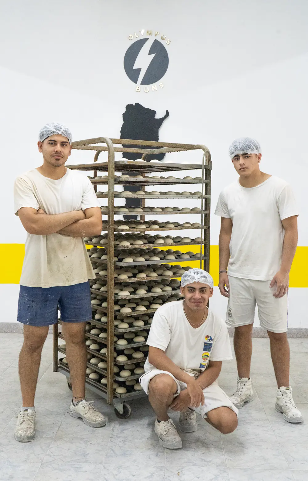 El equipo de Olympus Buns junto al logo de la fábrica