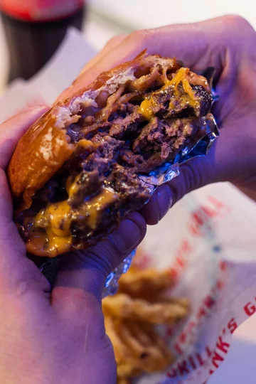Hamburguesa de Frank's Grill sostenida con las dos manos